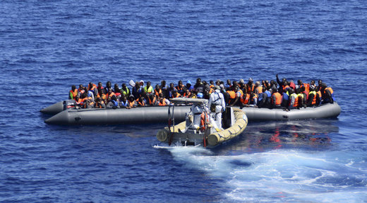 Migrants sit in their boat during a rescue operation by Italian Navy vessels off the coast of Sicily