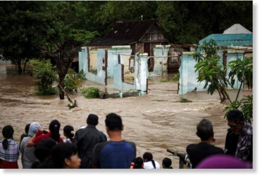  People stand in front of a flooded area in Kampung Sewuresidential area in Solo, Central Java province, Indonesia, June 19, 2016. 