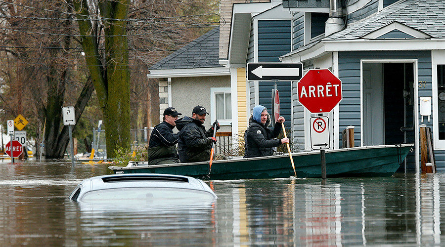 People row a boat in a flooded residential area in Gatineau, Quebec