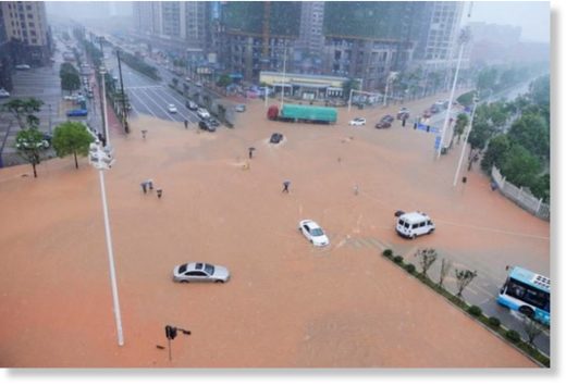 Pedestrians and vehicles cross a flooded street during heavy rain in Changsha, Hunan province, China, July 1, 2017.