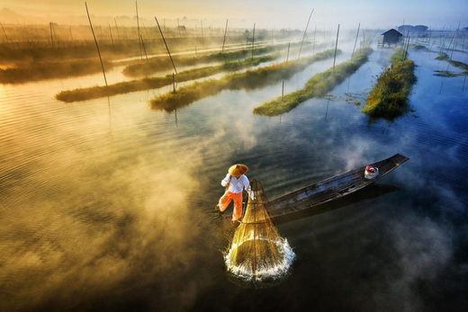 An Intha fisherman sets up his net to fish as he paddles his boat with a unique leg-rowing technique in Mayanmar’s Inle Lake.