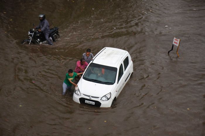 Indian men push a car through a flooded street in Ahmadabad.